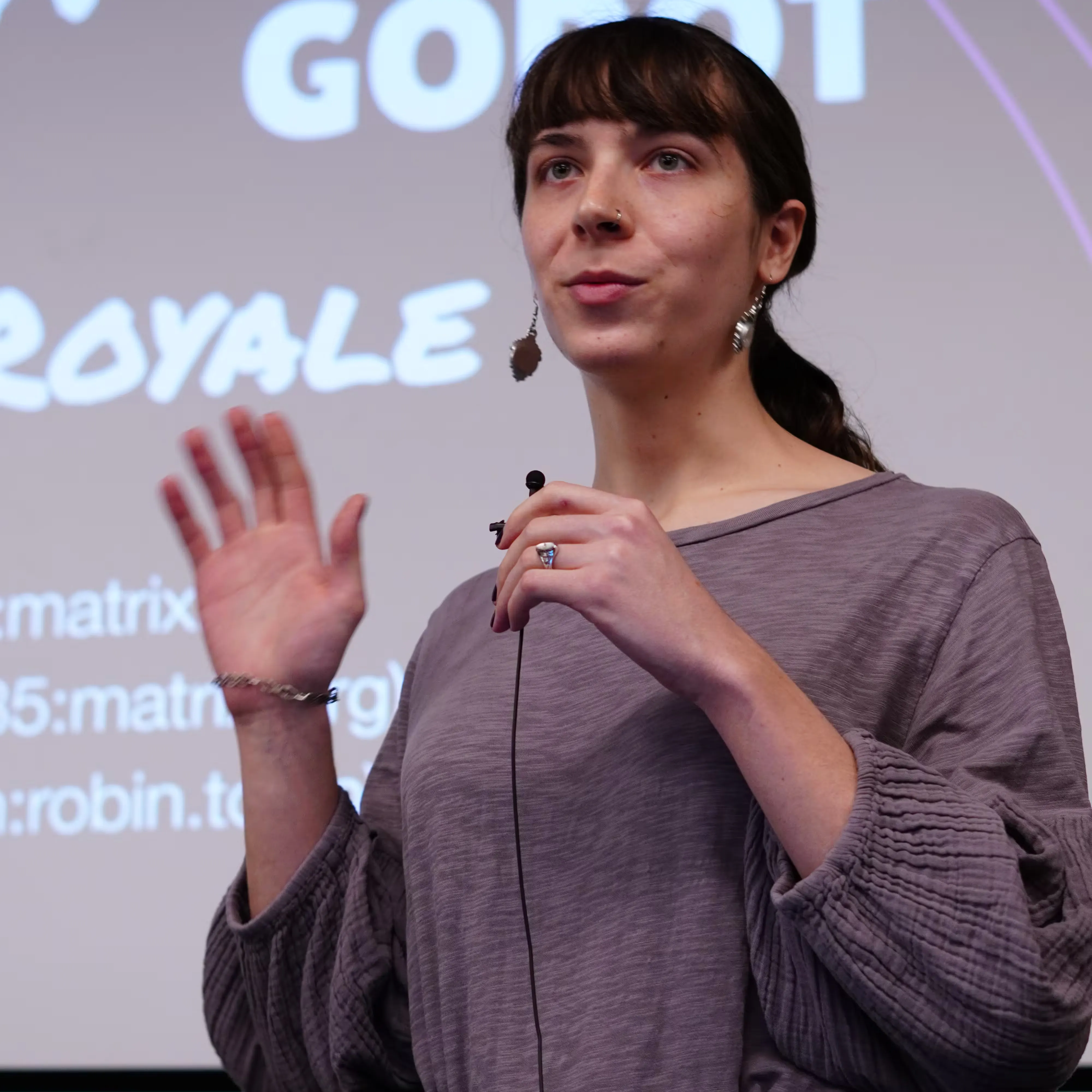 A portrait of Robin, a woman giving a talk in front of their slides. In the background we can read the word "Godot" on her slides.