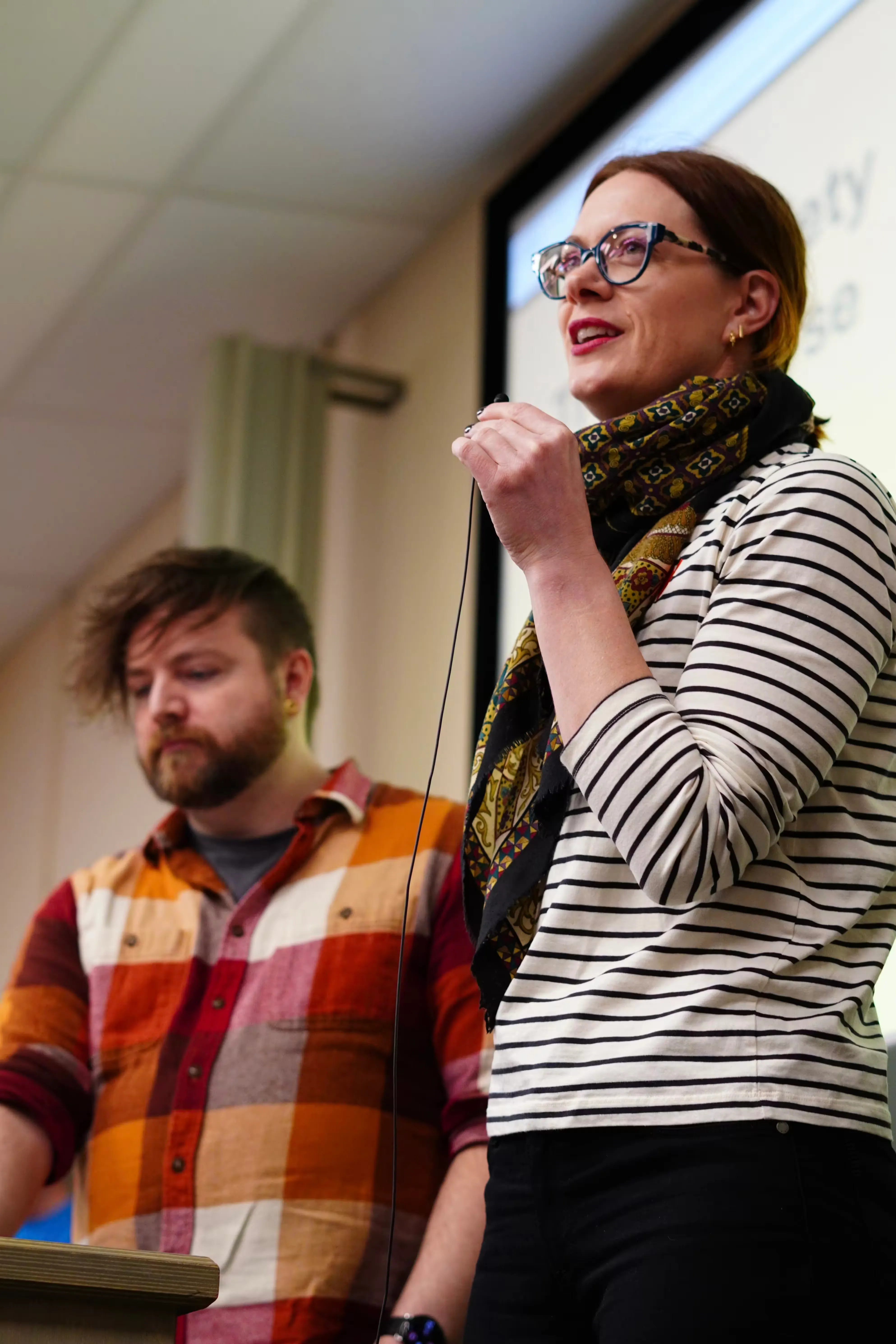 A portrait of Cassidy and Anne, two speakers giving a talk in front of their slides